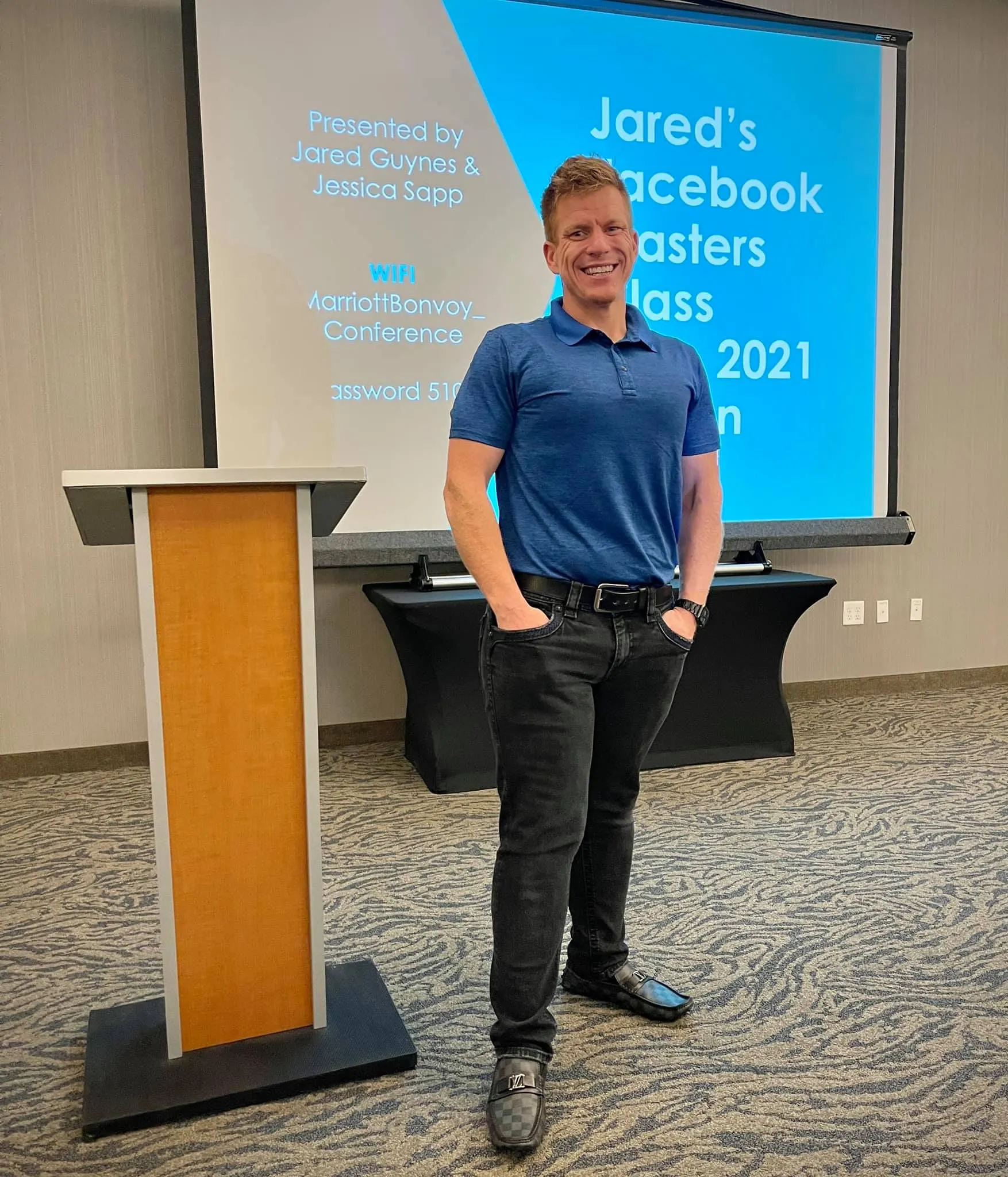 Jared Guynes standing beside a lectern in front of a Jared's Facebook Masters Class title slide